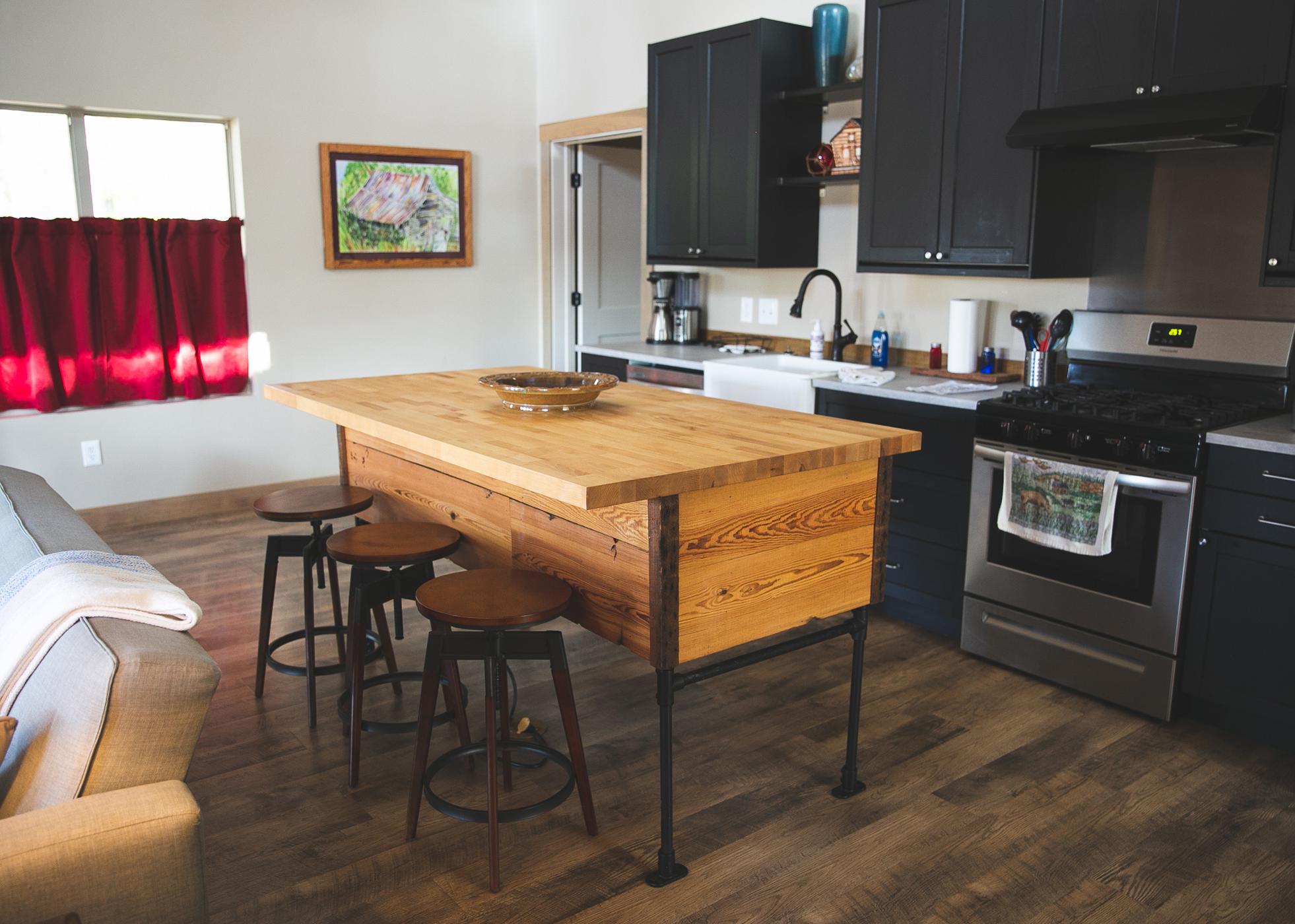 A serving island and three stools sit in a kitchen.