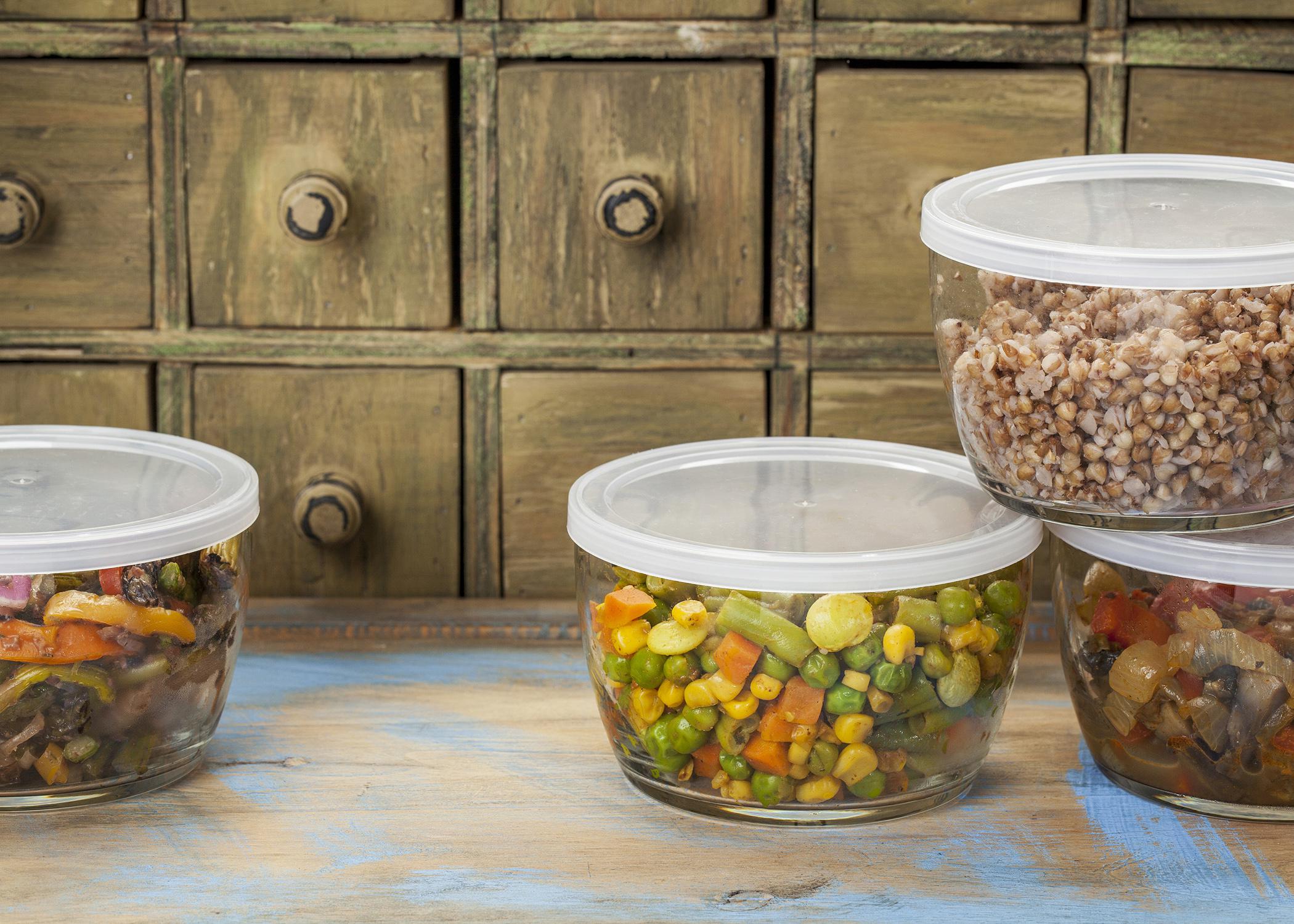 Four glass containers with plastic lids contain food leftovers.
