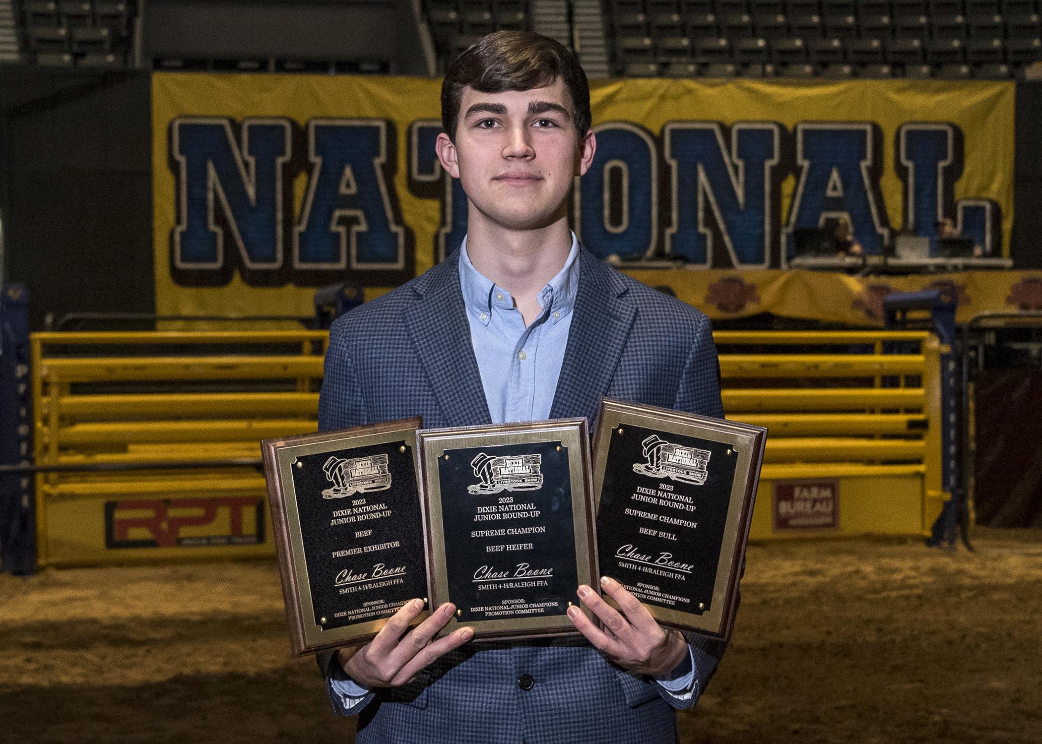 A young man holds three plaques.	