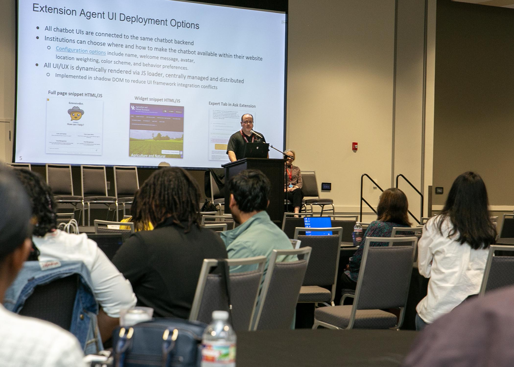 Two people are on stage during a presentation.