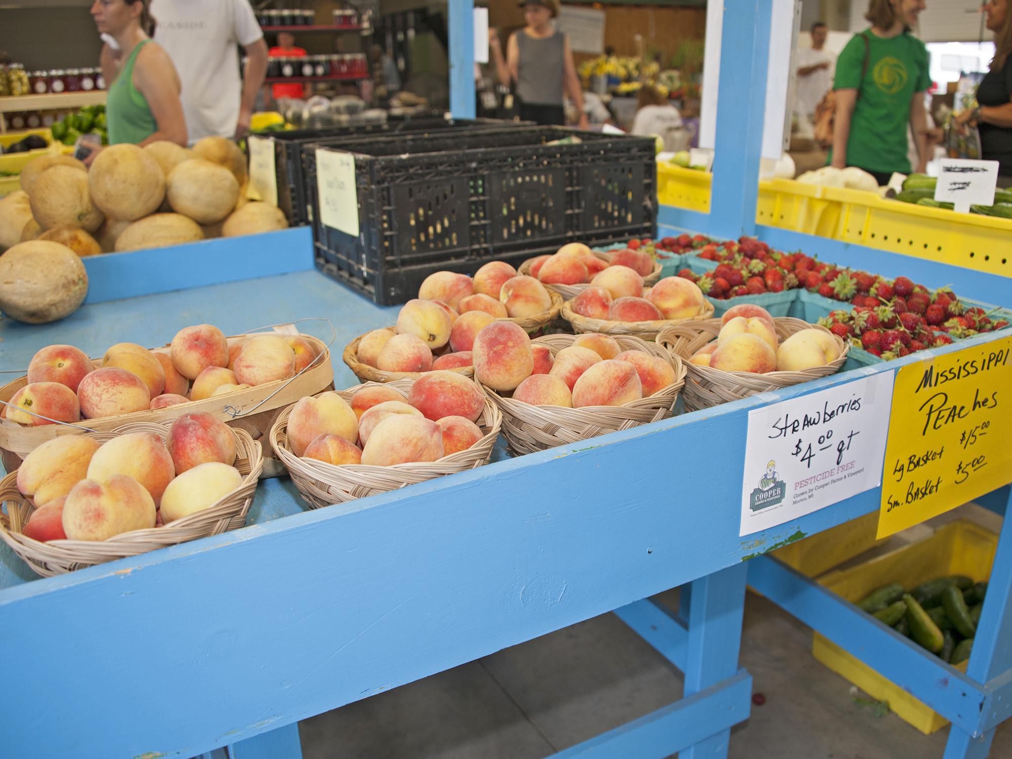 Peaches displayed for sale on a bright blue table. Production and sale of peaches, strawberries and other fruit and vegetable truck crops are on pace to be strong once again this year. (File photo by MSU Extension/Kat Lawrence)