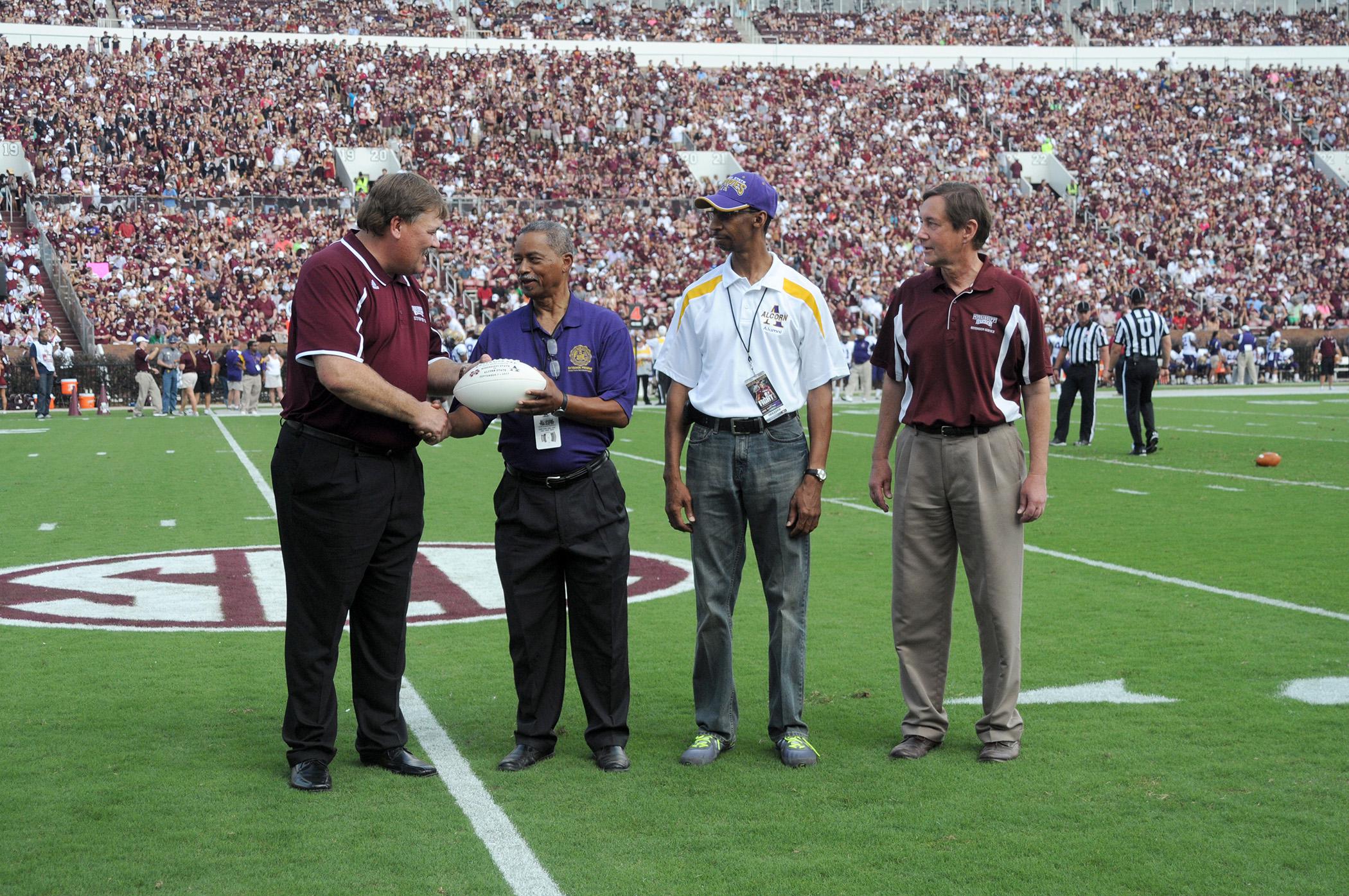 Mississippi State University Extension director Gary Jackson took to the field Sept. 7, 2013, at the MSU home opener to present a commemorative football to visiting Alcorn State University partners. From left are Jackson; Alcorn Extension administrators Dalton McAfee and Anthony Reed; and Gregory Bohach, MSU vice president for the Division of Agriculture, Forestry and Veterinary Medicine. (Photo by MSU Ag Communications/Kat Lawrence)