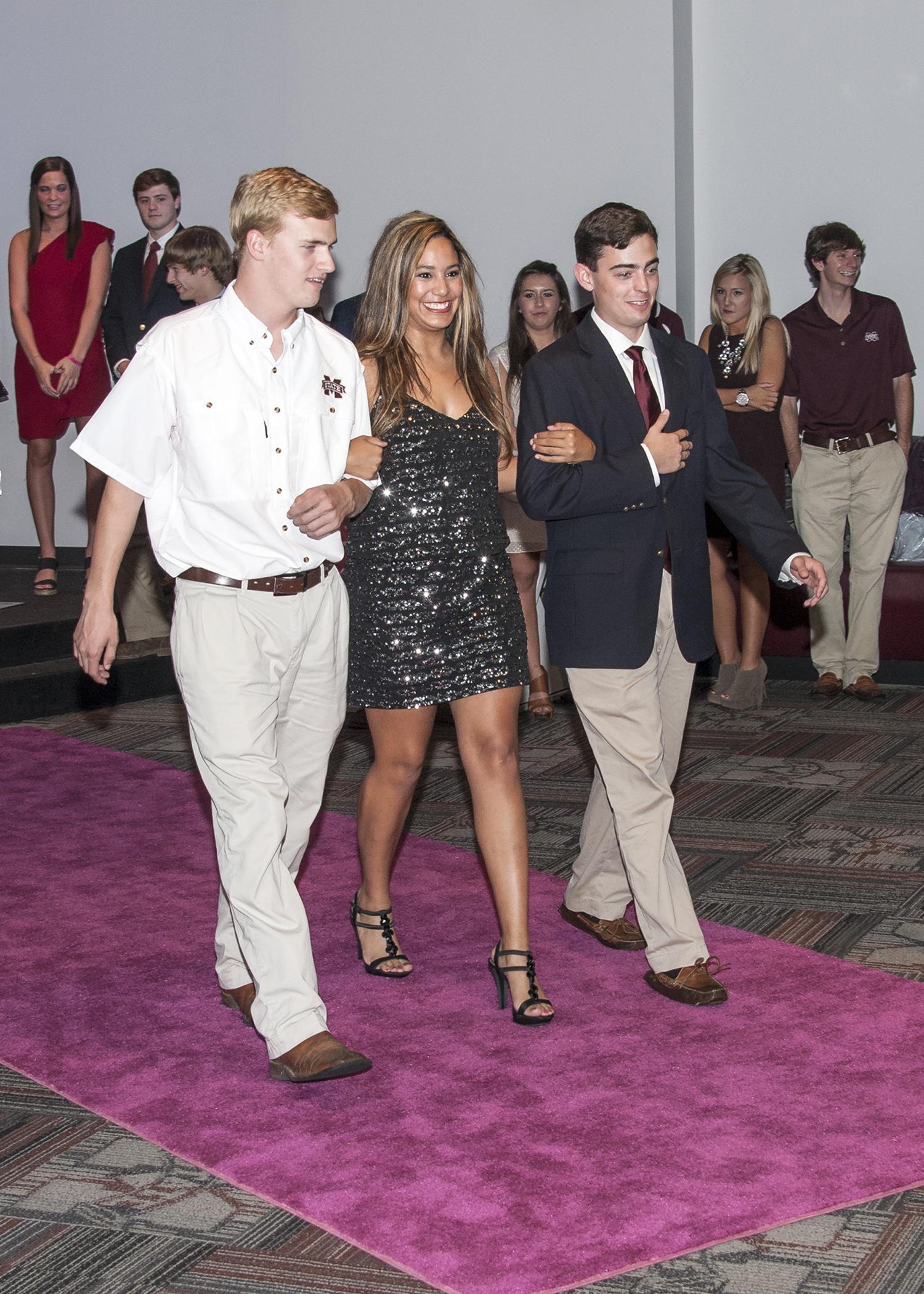 Mississippi State University junior Ashley Rowland of Gulfport, escorted by Justin Lofton of Bentonville, Ark., left, and John Dergin May of Madison, models a Milly gown at the Rent the Runway fashion show on Oct. 16, 2013. The event was sponsored by Fashion Focus, the campus service club for students interested in apparel, textiles and merchandising careers. (Photo by MSU Ag Communications/Scott Corey)