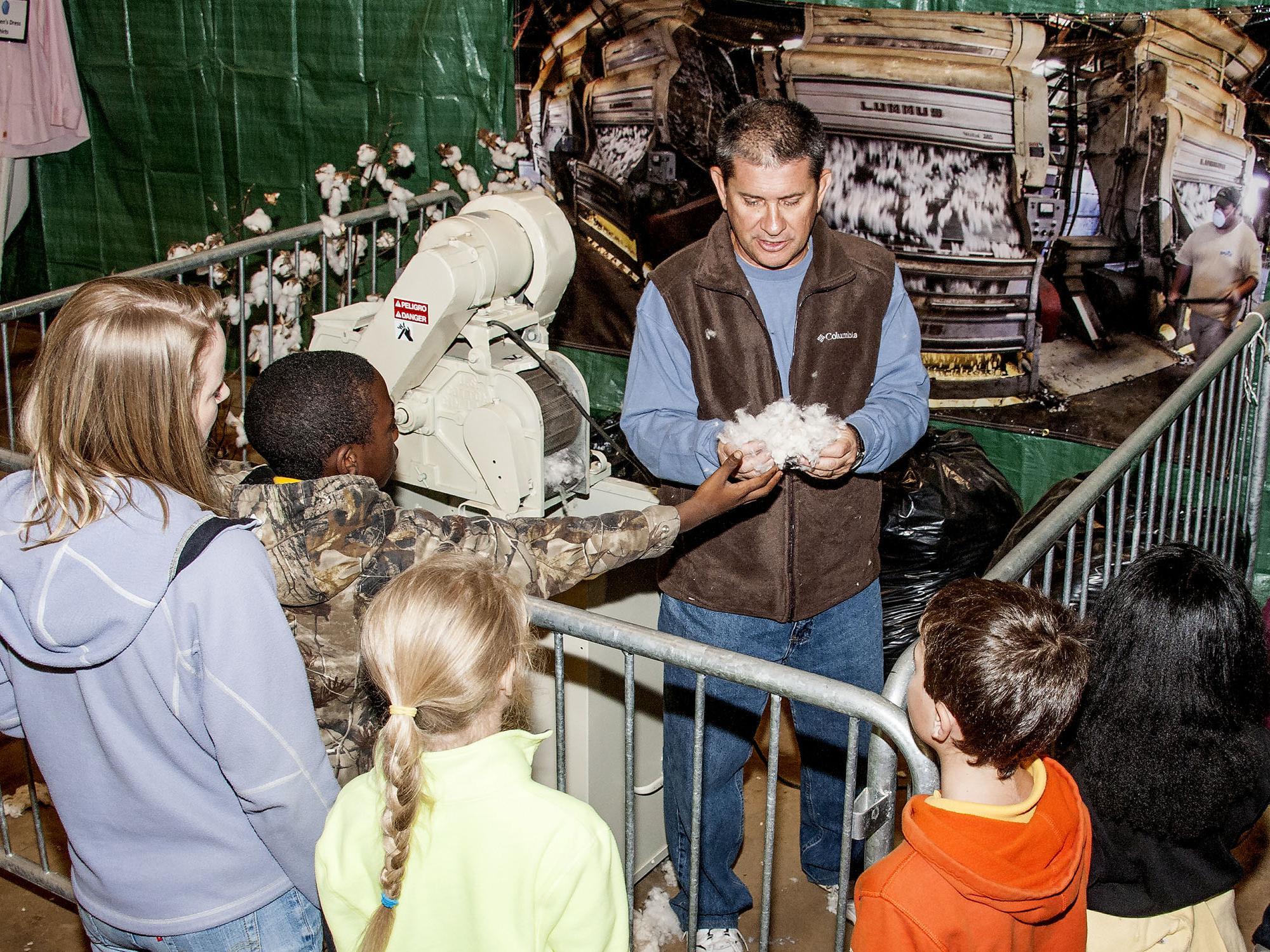 Dennis Reginelli, an area agronomic crops agent with the Mississippi State University Extension Service, explains the ginning process that helps create cotton fabrics. Addressing primarily third-graders at the Mississippi Horse Park on Nov. 7, 2013, Reginelli and the cotton exhibit were part of Farmtastic, a four-day educational program designed to help children learn the sources of their food, clothing and other products. (Photo by MSU Ag Communications/Scott Corey)