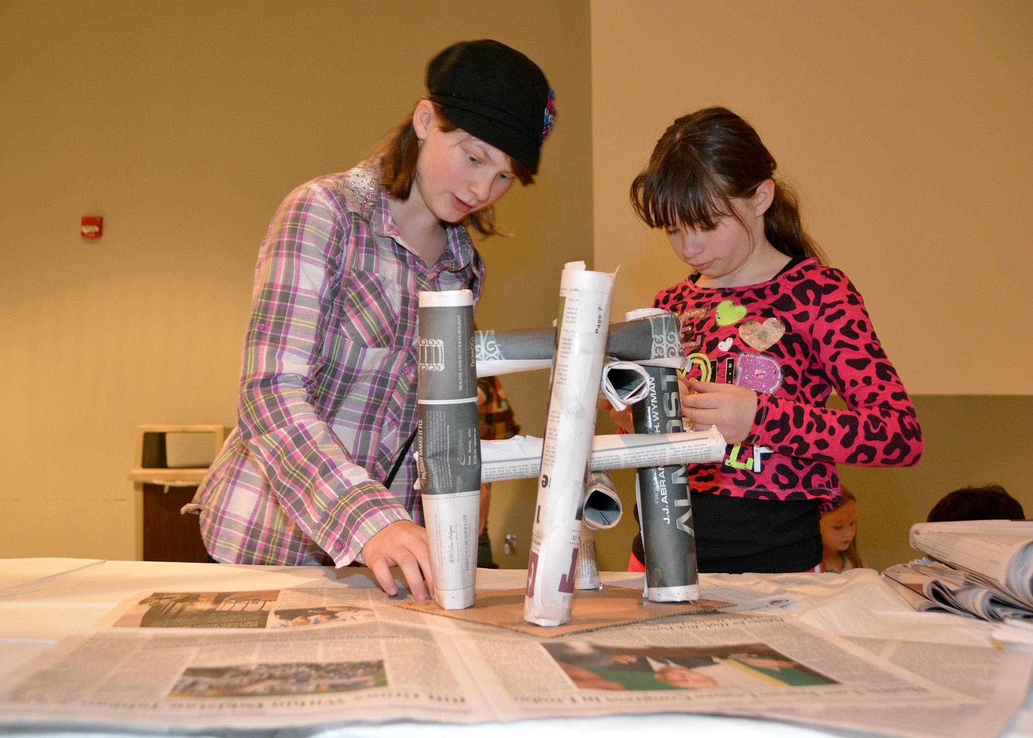 Lisa Cain, 11, and Mary Jane Cain, 10, use rolled-up newspaper to build a paper table at the Mississippi State University Mechanical Engineering Service Learning Showcase Nov. 20. 4-H members tested educational projects developed by MSU students in partnership with MSU’s Center for the Advancement of Service-Learning Excellence. (Photo by MSU Ag Communications/Bonnie Coblentz)