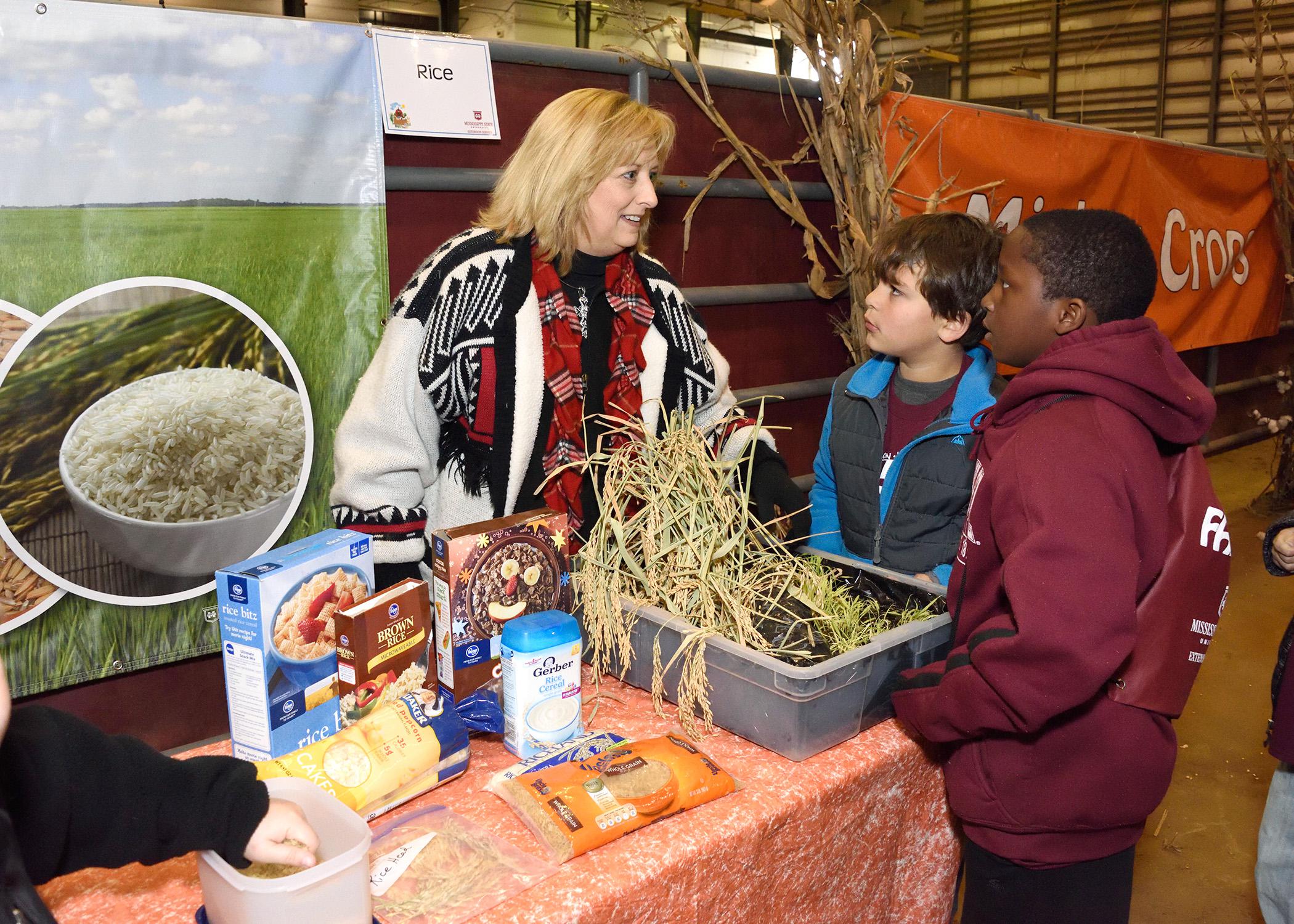 Lisa Stewart, an agent with the Mississippi State University Extension Service in Webster County, explains the importance of rice to Clayton Griffin and Jalen Washington, third-graders from Houston Upper Elementary School, at the FARMtastic event at the Mississippi Horse Park near Starkville on Nov. 13, 2014. (Photo by MSU Ag Communications/Kevin Hudson)