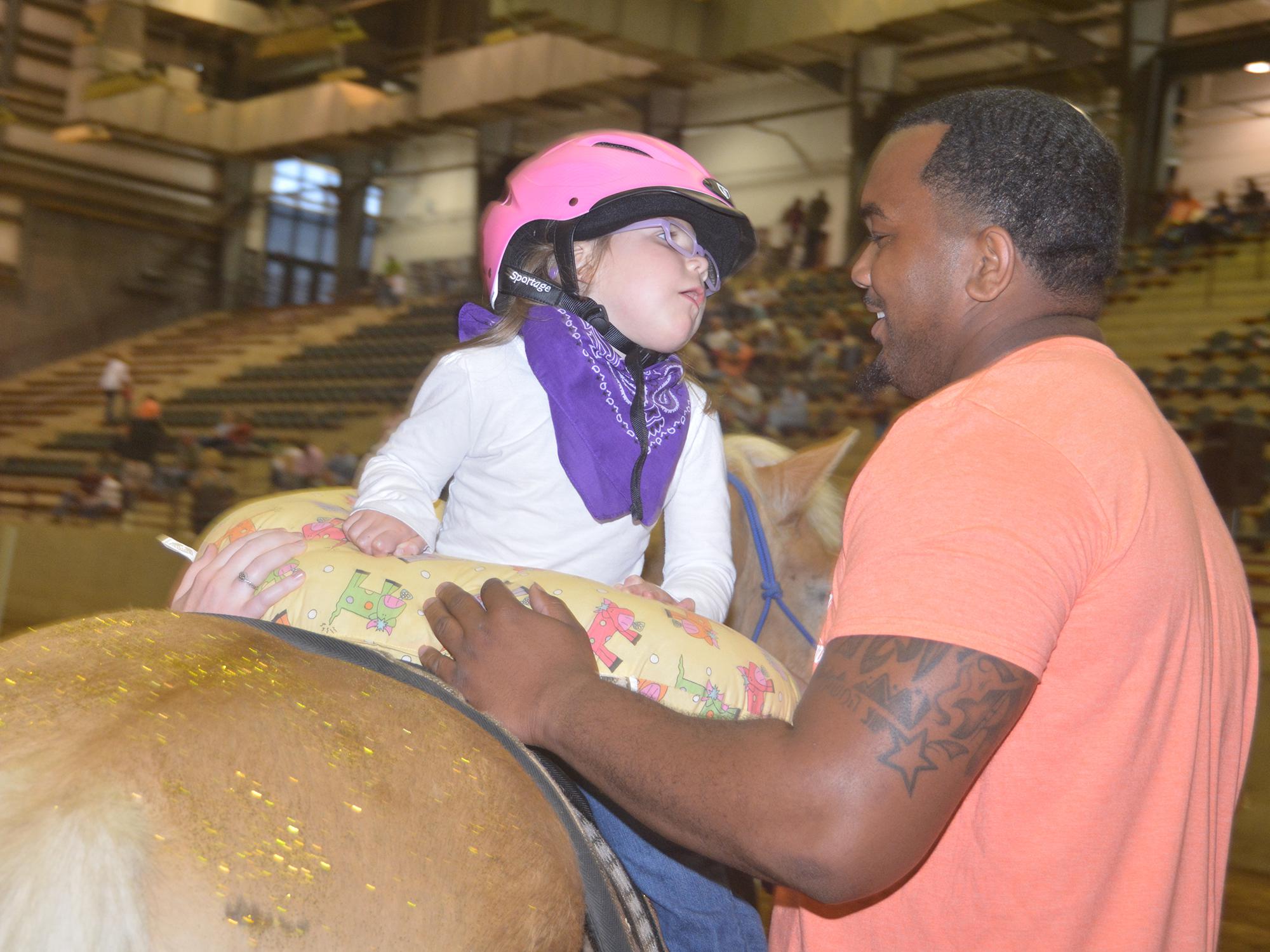 Emma Welch, 5, cannot take her eyes off her side walker, Rufus Warren, a senior in the Mississippi State University School of Human Sciences. The two were demonstrating hippotherapy activities during the Therapeutic Riding Expo at the Mississippi Horse Park near Starkville April 19, 2016. (Photo by MSU Extension Service/Linda Breazeale)