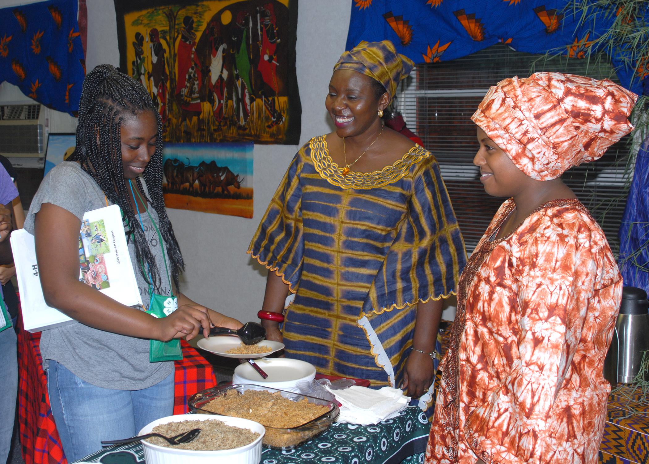 Lee County 4-H member Kennedy Armstrong selects samples from Kenyan dishes prepared by Carolyn Kobia, center, and Adey Efrem during the first International Village, held during state 4-H Congress at Mississippi State University on May 27, 2015. (Photo by MSU Ag Communications/Linda Breazeale)