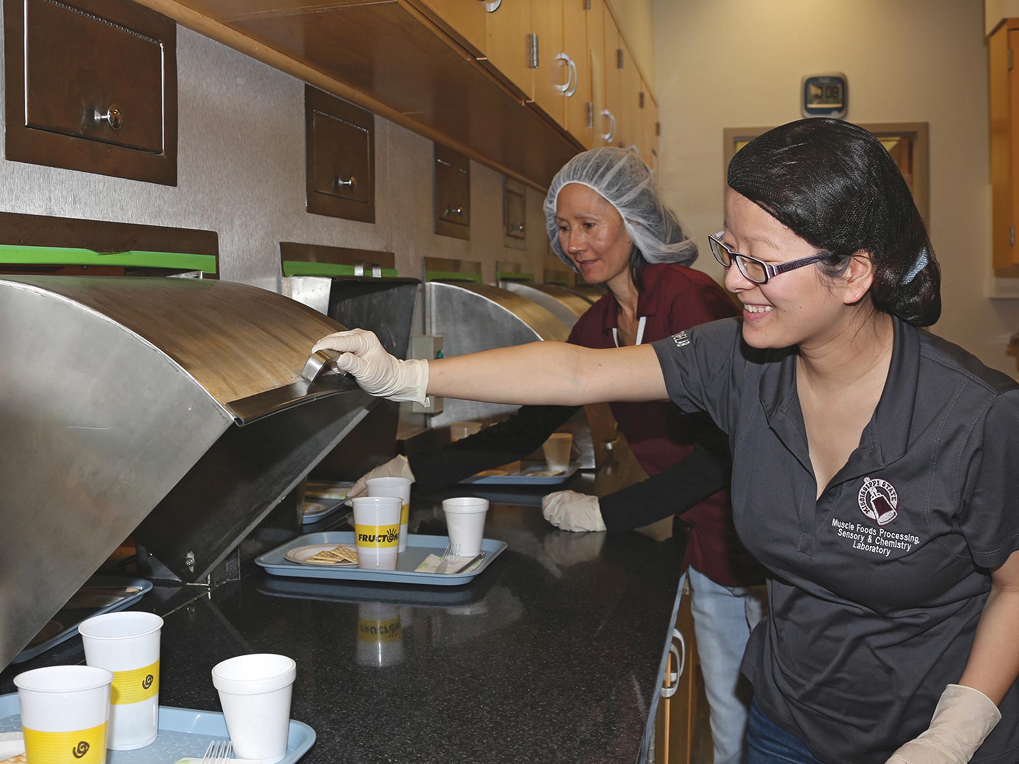 Doctoral student Yan Campbell, front, and research associate Vi Jackson serve trays to consumer panelists, who evaluate the food samples and determine how acceptable they are. (Photo by MSU Extension Service/Kat Lawrence)