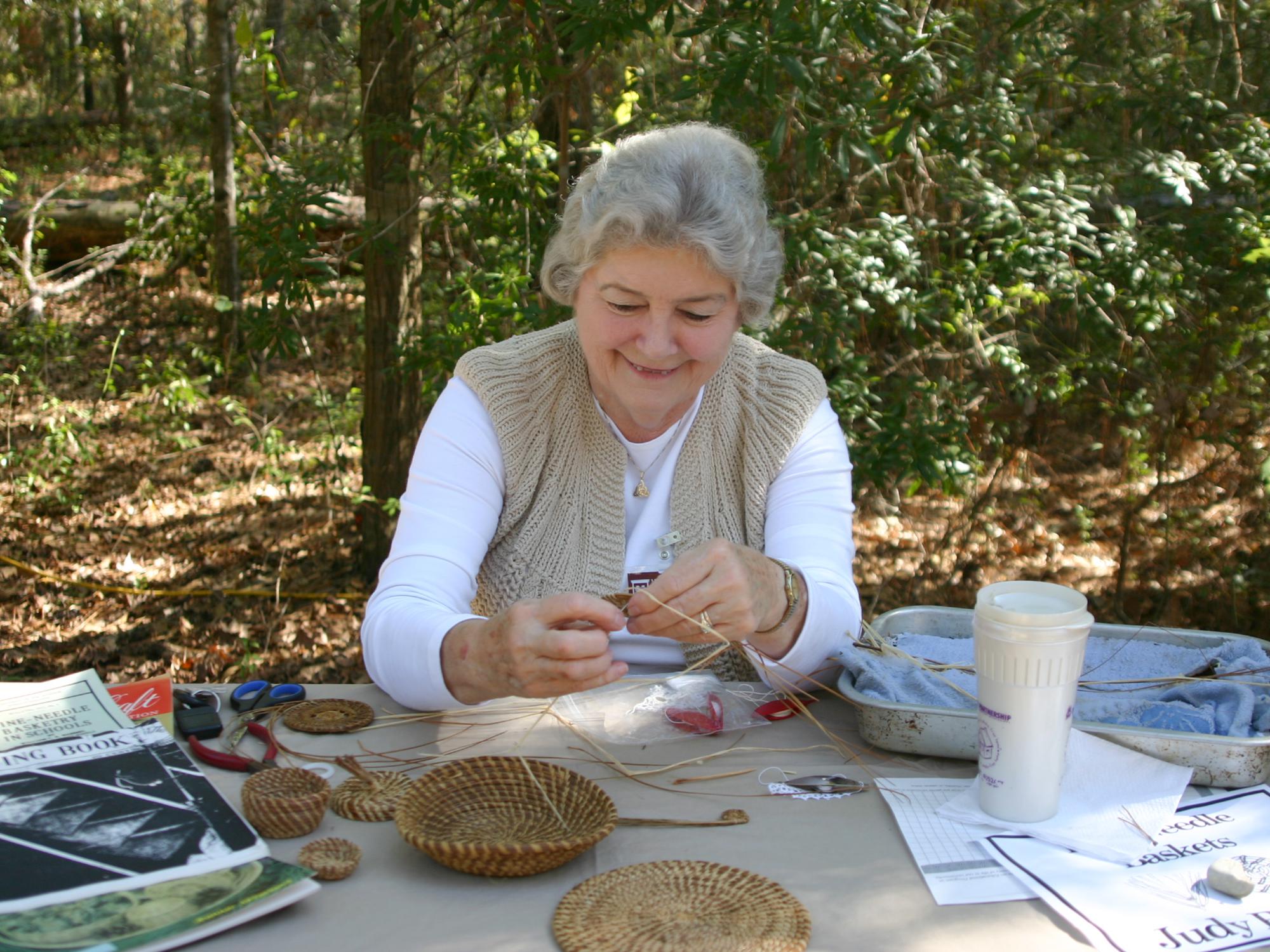 Judy Breland, Mississippi State University Extension Service agent in Stone County, demonstrates pine needle basket weaving at the 2015 Piney Woods Heritage Festival at the MSU Crosby Arboretum in Picayune, Mississippi. The 2016 festival is set for Nov. 18 and 19. (Photo by Mississippi State University Extension Service/Pat Drackett)