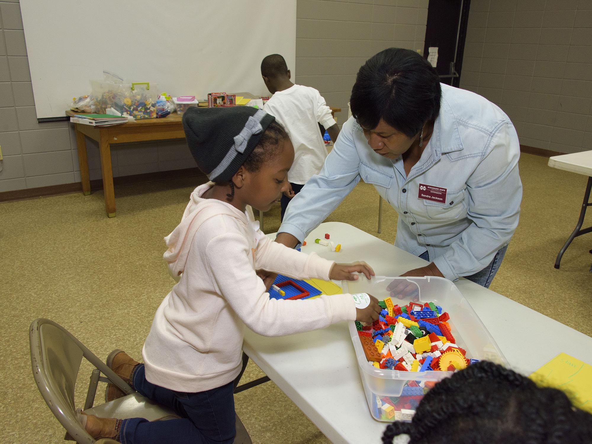Sandra Jackson, an agent of the Mississippi State University Extension Service in Winston County, helps 6-year-old Akilah Goss assemble a Lego maze March 16, 2017. Jackson was the first agent to teach the 4-H Lego Engineering Club curriculum, which is a STEM program geared toward 4-H’ers aged 5 to 7. (Photo by MSU Extension/Kevin Hudson)