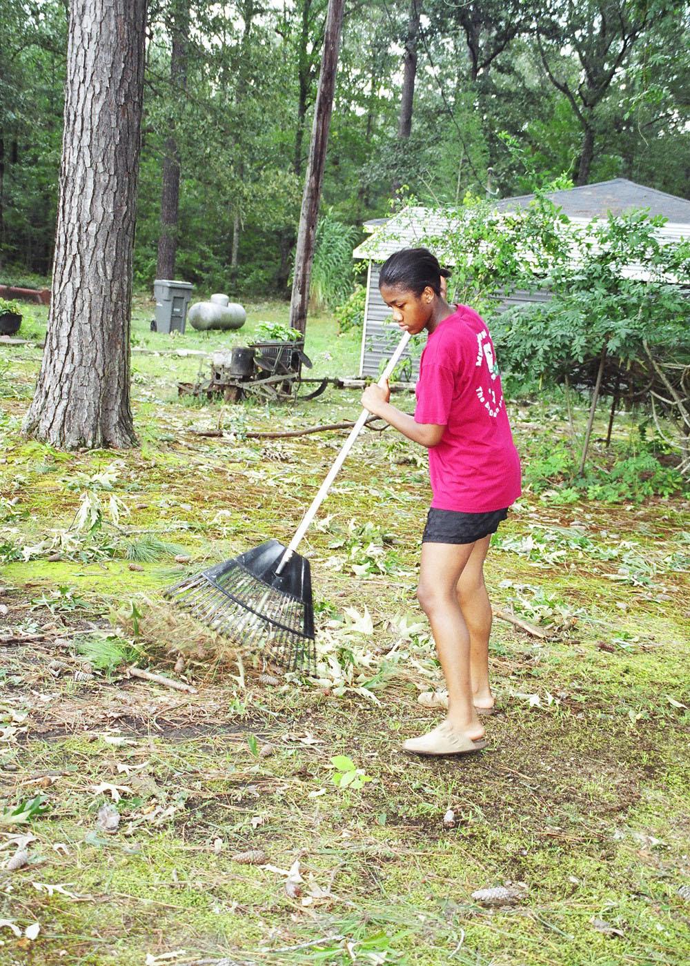 Andrea Brown, a 14-year-old Oktibbeha County 4-H member, rakes limbs and debris in the yard of a senior adult friend in the Bell Schoolhouse Community. Many Mississippians are depending on the help of friends and family to assist in cleaning up in the wake of Hurricane Katrina.