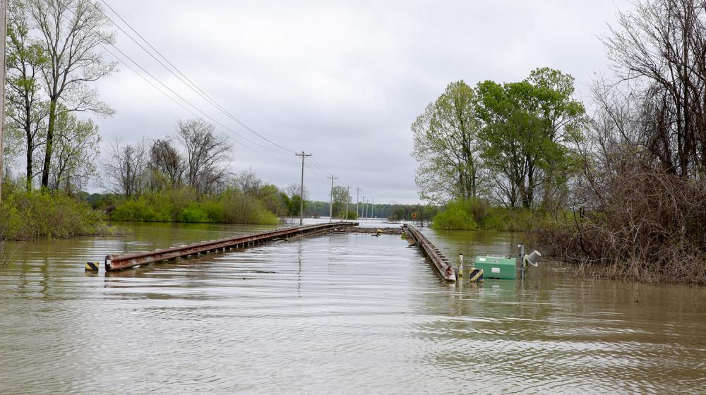 Flood waters have completed covered a road with only the top rails of the bridge visible.