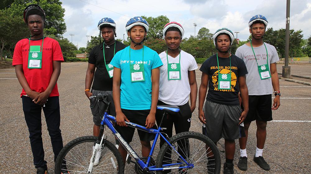 Young men in parking lot with bicycle.
