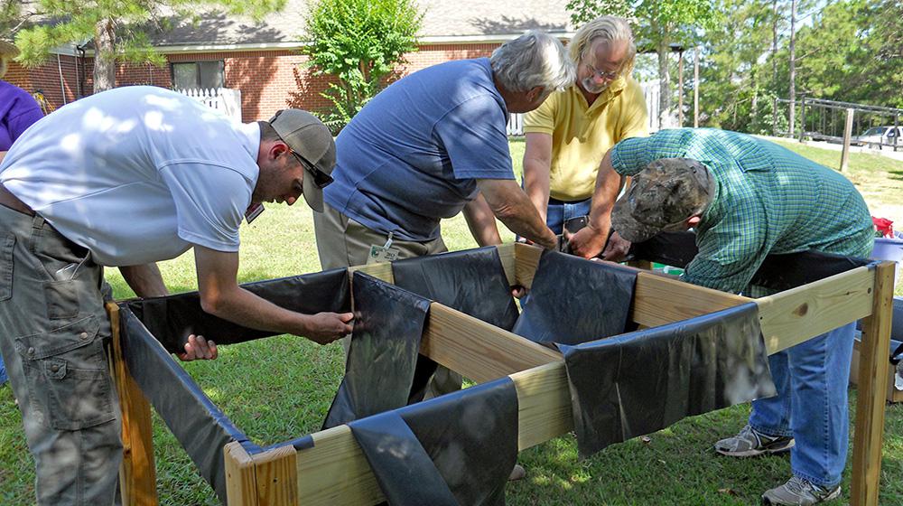 From left, Lamar County Extension Agent Ross Sadler, Pine Belt Master Gardener Paul Cavanaugh, Lamar County Technical Center teacher and volunteer Ken McCoy and Pine Belt Master Gardener intern Cecil Chambliss prepare a handicapped-accessible raised bed for plants. The group built two beds for residents of The Windham House of Hattiesburg, an assisted-living facility for seniors on May 28 and will return monthly to help with the beds and teach workshops. (Photo by MSU Ag Communications/Susan Collins-Smith)