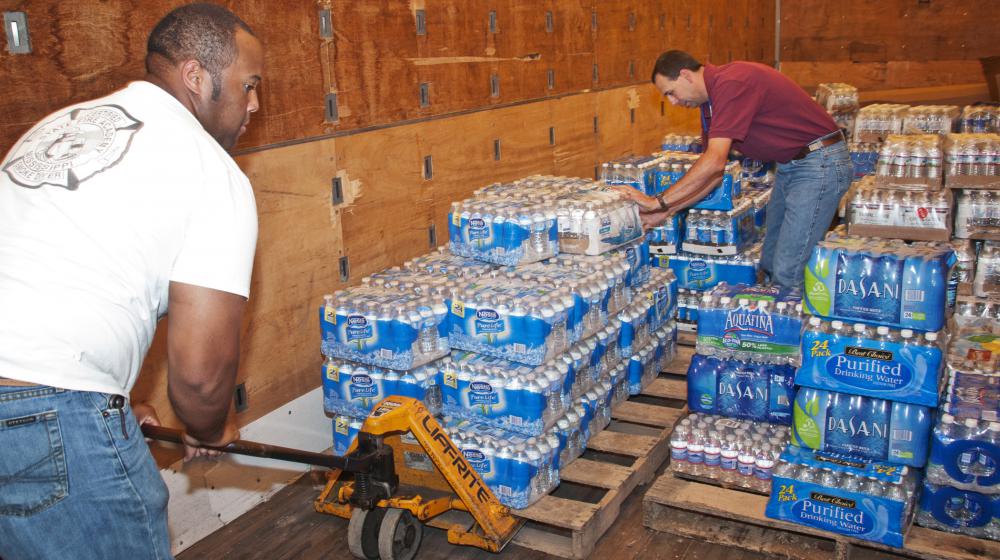 B.J. McClenton, Monroe County Extension director (left), and Charlie Stokes, area Extension agent (right), unload water from a semi-trailer to distribute to tornado victims in Monroe County. MSU Extension Service employees are storing and distributing supplies to those affected by the April 26 and 27 tornadoes. (Photo by Scott Corey) 