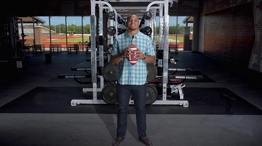 Dak holding football in front of weights during the during the Colon Cancer Screening PSA shoot.