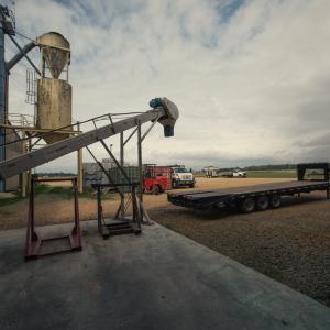 Grain bin equipment, trucks, and trailers in an open lot.