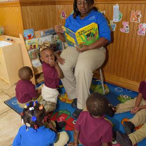 A woman reading a book to toddlers.