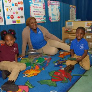 A woman smiling with two smiling children.