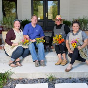 Four people sitting on steps and holding bunches of flowers in their laps.