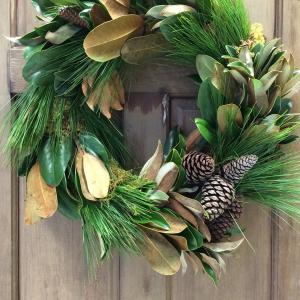 A magnolia and pine wreath on a wooden door.