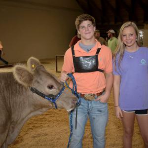  A teenage boy and girl stand beside a cow at the Mississippi State Fair. 