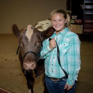A young girl stands beside a cow at the Mississippi State Fair.