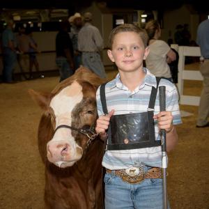 A young boy stands beside a cow at the Mississippi State Fair.