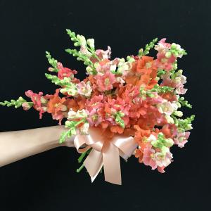 A bridesmaid’s bouquet of coral-colored snapdragons with bow.