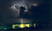 A brilliant streak of lightning flashes over Suttle Hall, north of Mississippi State University, during a summer storm in this archived photo. (Photo by MSU Geosciences/Michael Brown)