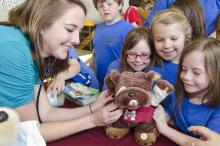 Alex Long (back, left) looks on as (left to right) Maddi Capps, Abby Hood and Addi Capps from Mooreville Elementary School present a bulldog to Mississippi State University College of Veterinary Medicine student Janet Koester. Koester and her classmates tended to injured toys on April 13 at the teddy bear clinic, part of CVM's annual open house celebration. (Photo by MSU College of Veterinary Medicine/Tom Thompson)