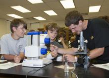 Gage Hensarling, 11, left, and Jac Cooper, 10, watch Edward Entsminger extract a plant disease sample to examine under the microscope. The group were participating in Mississippi State University's weeklong Bug and Plant Camp. (Photo by MSU Ag Communications/Kat Lawrence)