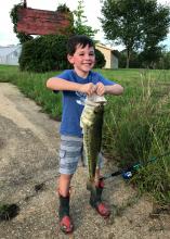 Young boy in blue shirt holding large fish.