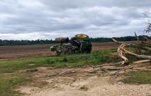 Green tractor flipped on its side in a field.