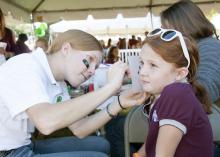 4-H, the youth development arm of the Mississippi State University Extension Service, took part in MSU’s Homecoming celebration Oct. 20. 4-H’er Sara Burns of Lauderdale County paints the face of Rachel Singleton of Leflore County at a pregame tailgate party.  (Photo by MSU Ag Communications/Kat Lawrence)