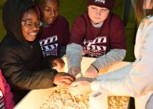 Third-graders from Houston Upper Elementary School, including, from left, Jamyrie Davenport, Sedrick Walker and R.J. Utz, pet a baby chicken held by a volunteer at the Mississippi State University Extension Service FARMtastic event at the Mississippi Horse Park near Starkville on Nov. 13, 2014. (Photo by MSU Ag Communications/Kevin Hudson)