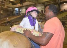 Emma Welch, 5, cannot take her eyes off her side walker, Rufus Warren, a senior in the Mississippi State University School of Human Sciences. The two were demonstrating hippotherapy activities during the Therapeutic Riding Expo at the Mississippi Horse Park near Starkville April 19, 2016. (Photo by MSU Extension Service/Linda Breazeale)