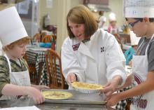Laura Brumbaugh (center), Mississippi State University Extension Service agent in Tate County, helps Harlan Tagert, left, and Walt Giesen, both of Starkville, finish their quiches on June 21, 2016, at the MSU Fun with Food Camp. The annual summer camp offers hands-on training and educational field trips for 3rd- to 6th-grade children to learn about nutrition, cooking and food safety. (Photo by MSU Extension Service/Michaela Parker) 