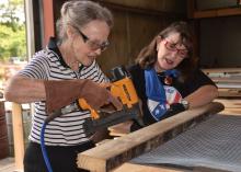 Margaret Thomas and Vicky Foster, both Pine Belt Master Gardeners, staple hardware cloth to the bottom of a salad table during a workday in Purvis June 19, 2014. Over the past year, the group has constructed more than 100 tables, some of which they have donated to non-profit organizations, nursing homes and community gardens. (Photo by MSU Ag Communications/Susan Collins-Smith)