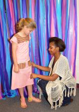 Mississippi State University student Iree Gordon of Jackson adjusts the dress she constructed for Oktibbeha County 4-H member Cory Freely before a special fashion show in Starkville, Mississippi, on May 2, 2015. (Photo by MSU Ag Communications/Linda Breazeale)