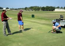 Mississippi State University Department of Plant and Soil Sciences senior research associate Wayne Philley, left, and MSU seniors Abram Diaz of D’Iberville and Aaron Tucker of Carthage measure how far a golf ball rolls over different varieties of bermudagrass at the R. R. Foil Plant Science Research Center Sept. 4, 2015. (Photo by MSU Ag Communications/Nathan Gregory)