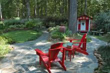 Red can be a difficult color to use in gardens, and the secret to its success sometimes lies in using it as an accent. The first thing that catches the eye in this outdoor room is the bright red Adirondack chairs. A short walk away is an idyllic children's play house of the same color. (Photo by Norman Winter)