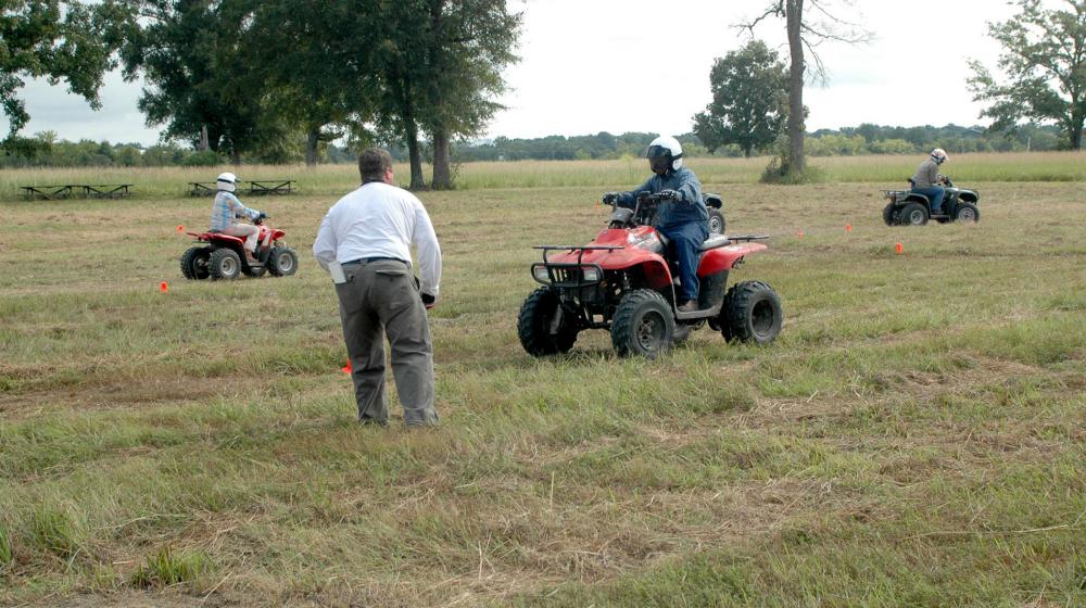 4-H ATV Safety Training Three young people drive ATVs on a marked course in a field during a safety training.