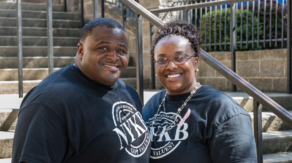 A man and woman standing in front of steps, smiling.
