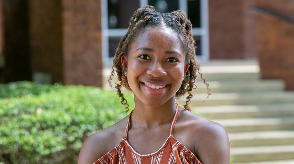 A young woman wearing a burnt orange and white striped shirt and smiling.