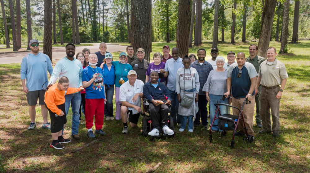 A group of people standing in front of trees.