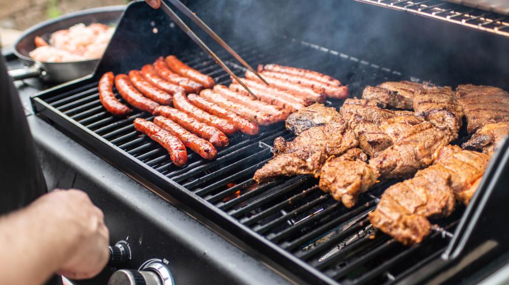 Grill with hotdogs and chicken on it