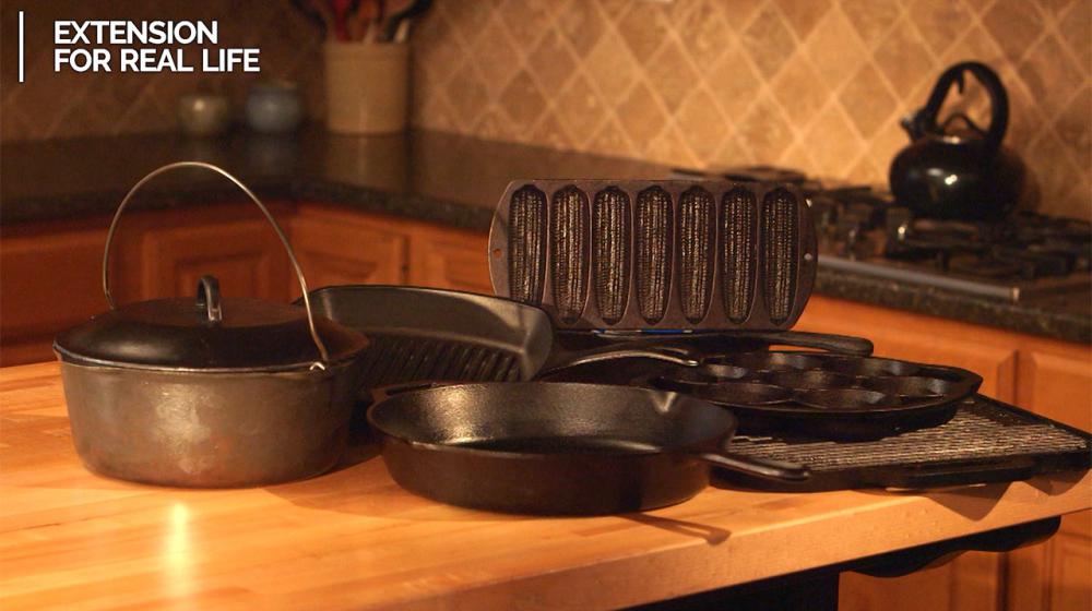 A grouping of various kinds of cast-iron cookware sit on a kitchen counter. 