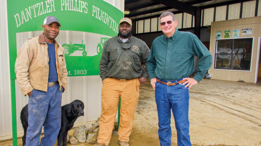 Three men and a black dog stand in front of a sign that reads "Dantzler Phillips Pilkinton."
